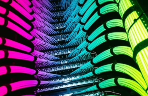 Technicien certifié procédant au câblage et au rangement d'une baie réseau serveurs en entreprise.